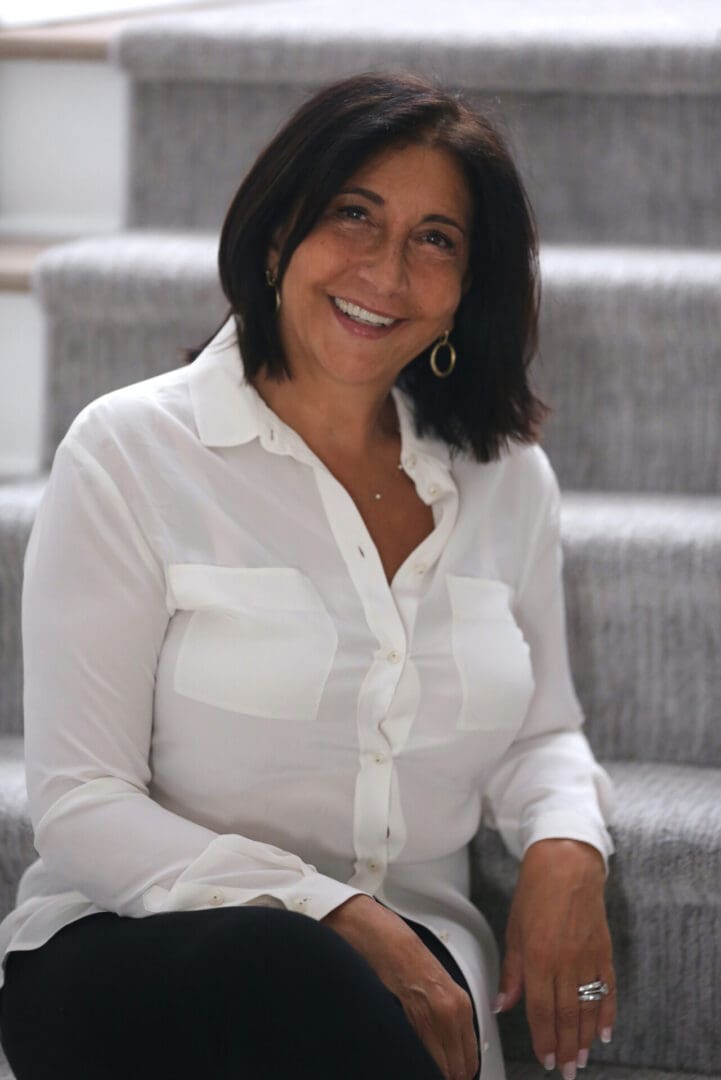 A woman in white shirt sitting on steps.