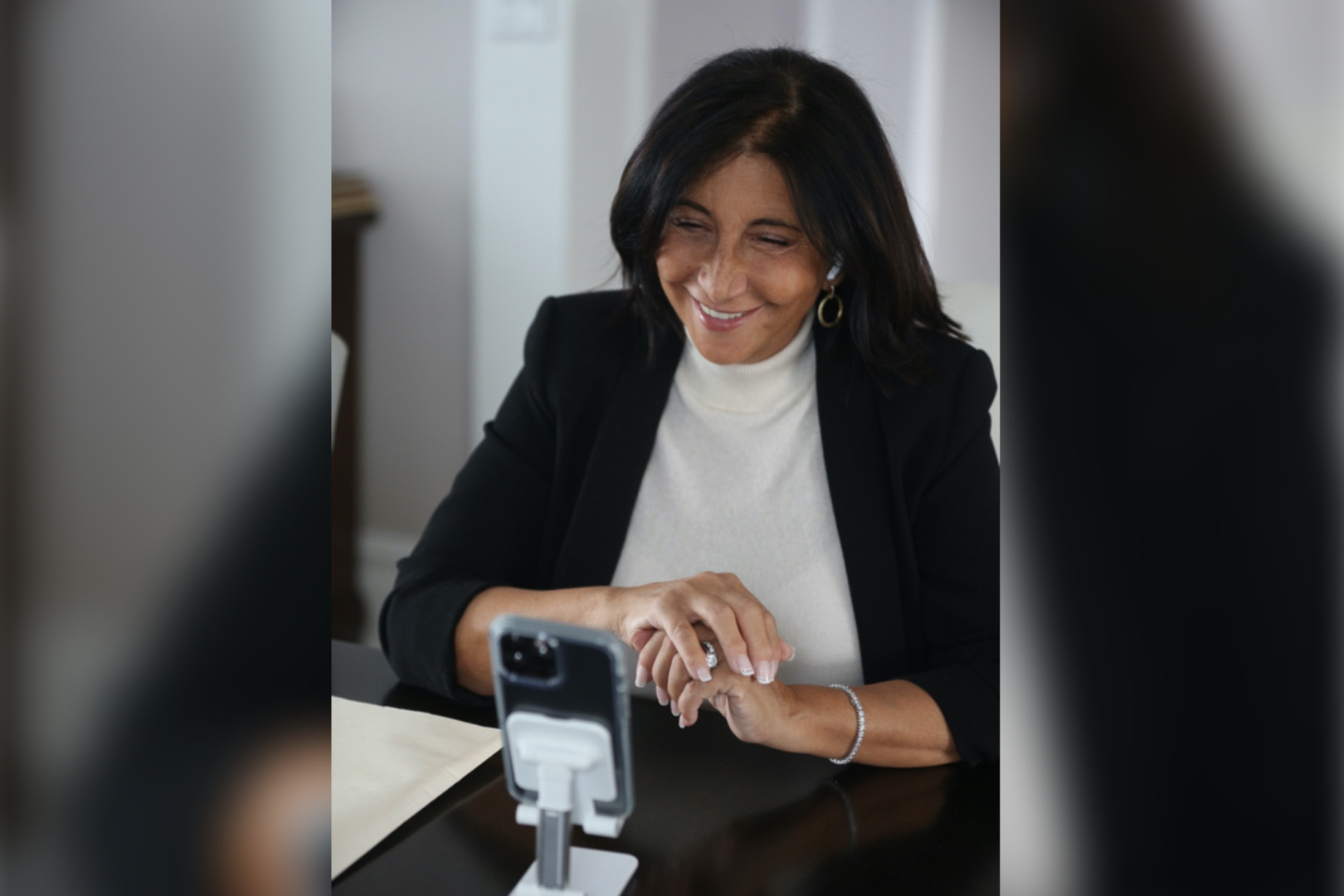 A woman sitting at a table with her phone.