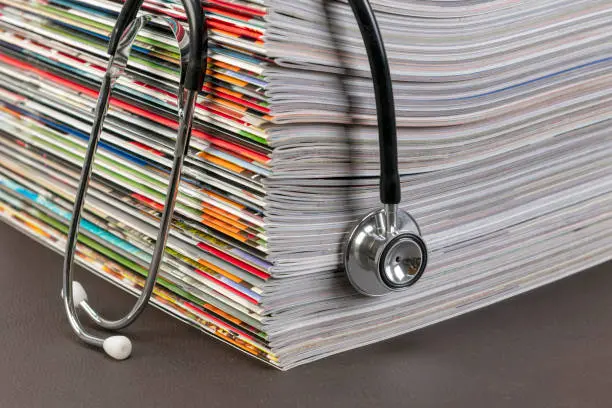 A stethoscope is on top of some magazines.