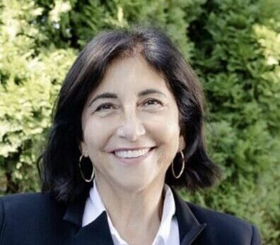 Smiling woman with dark hair outdoors.