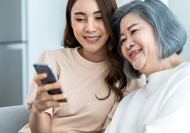 A woman and her mother looking at the phone.