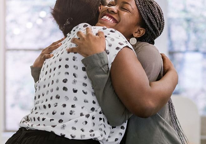 Two women hugging each other in a room.