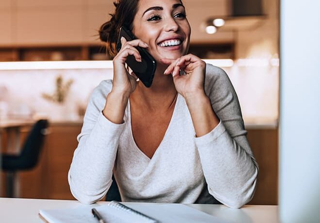 A woman sitting at a table talking on the phone.