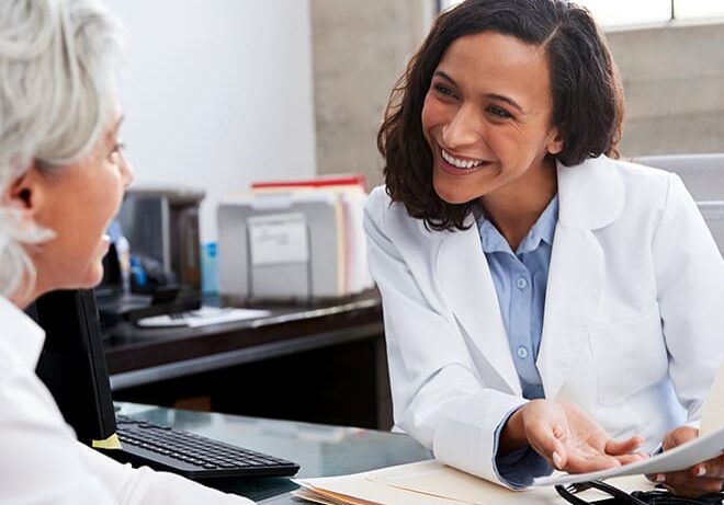 A woman in white coat sitting next to another person.