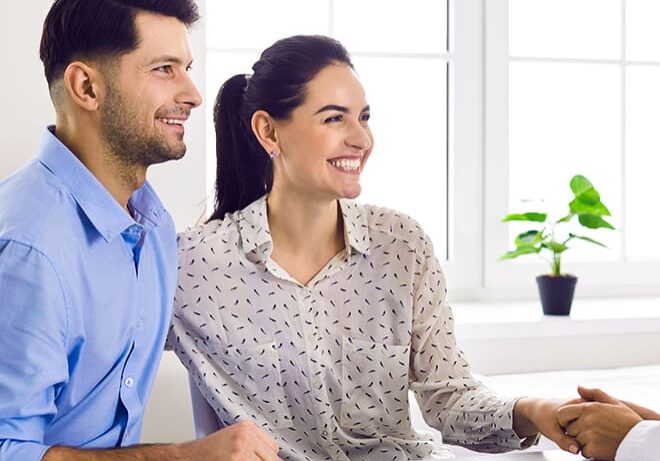 A man and woman sitting at a table with papers.