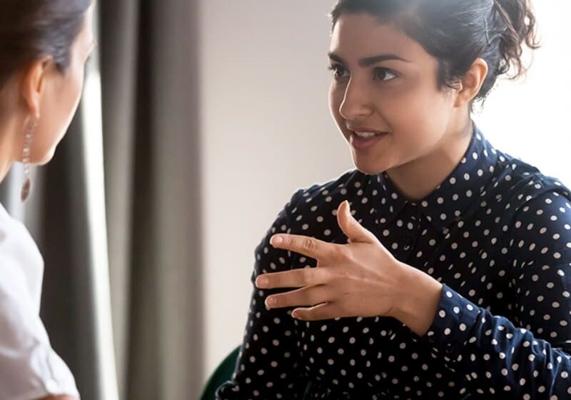 Two women talking, one gesturing.