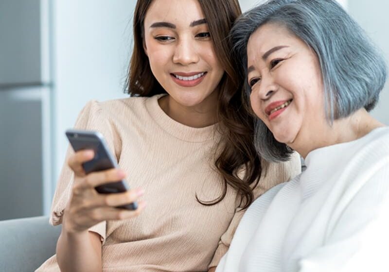 Two women look at a phone together.