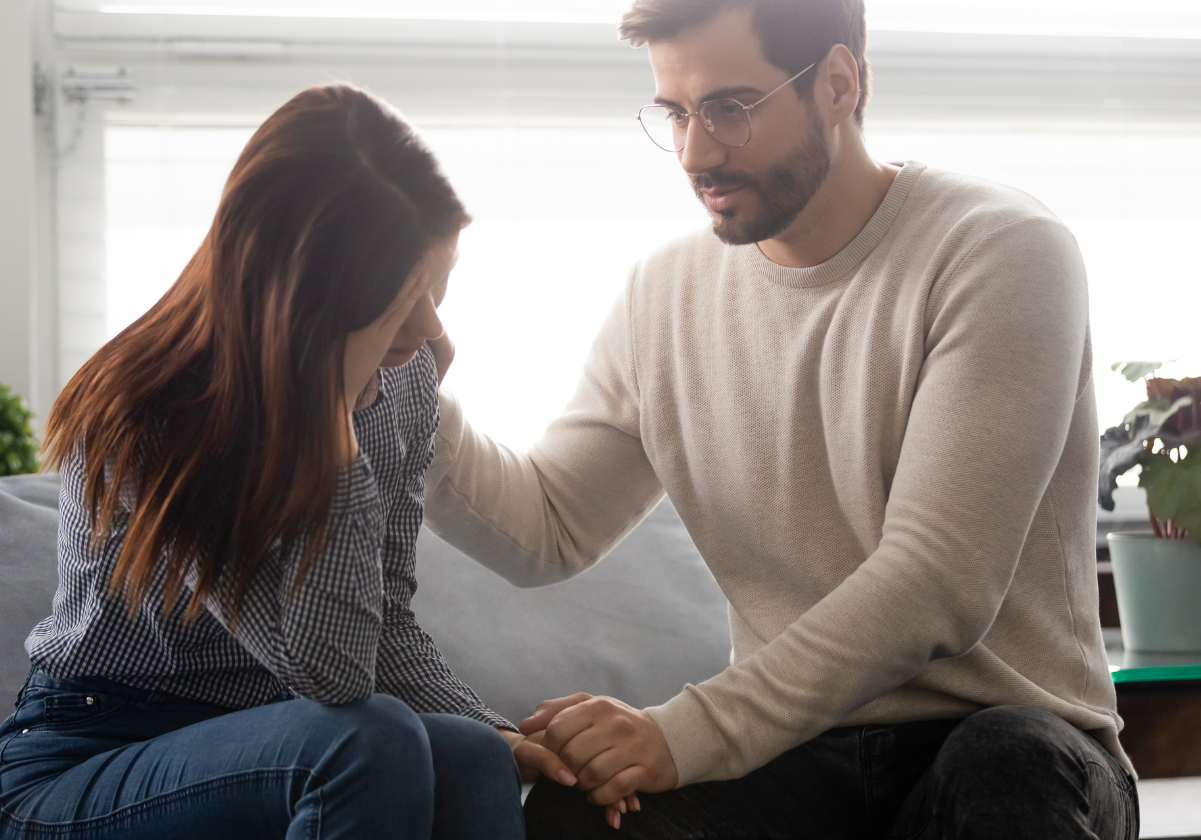 A man and woman holding hands while sitting on the couch.